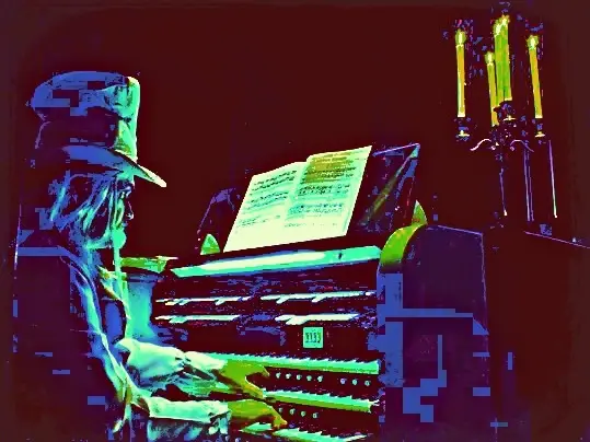 A figure playing an organ in saturated red, green, and blue light