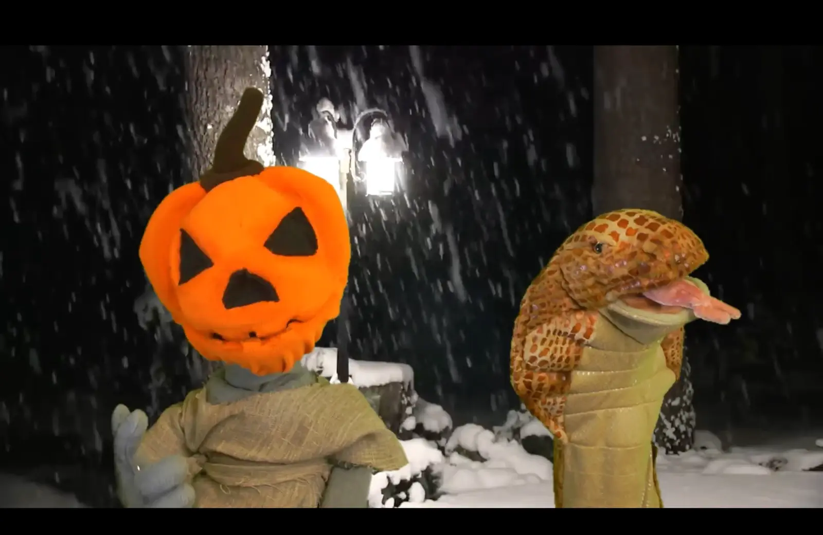 A pumpkin lantern and a small figurine in a snowy nighttime scene